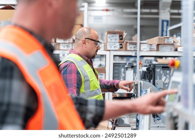 Male industrial worker working with manufacturing equipment in a production line factory, camera focused in the rear person. - Powered by Shutterstock