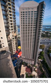 Male Industry Rope Access Worker, Wearing A Hard Hat Helmet, Working At Height And Abseiling Off Doing Inspection At Construction Building Site Near The Rock  In Sydney City CBD, Australia   
