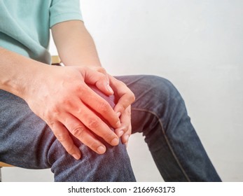 Male injured knee. Sore spot highlighted by red marker. Man touches him leg by hands. Close up on white background. Bone pain or knees around the knee , The man's hand is holding the knee area.