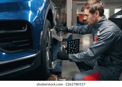 Male inspecting wheel alignment in the workshop