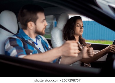 Male instructor controlling and checking during studying in school. Young woman driving and looking at the road. Driving test, driver courses, exam concept
