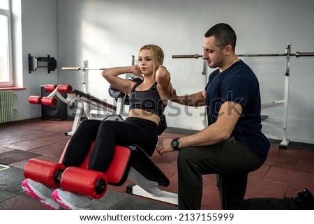 Male instructor exercising with his female client at gym. woman working about the optimal training program