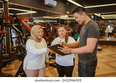 male instructor explaining workout plan for his trainee in gym - Powered by Shutterstock - Get 15% off with code: PIKWIZARD15