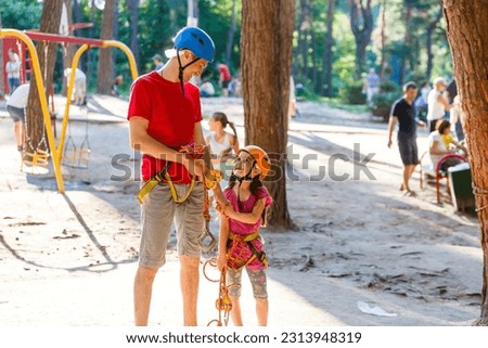 male instructor helps the child on the rope road in the training camp.