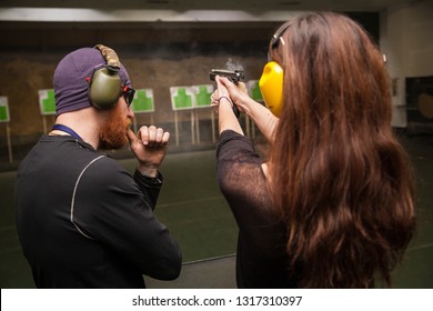 Male Instructor Teaches A Girl To Shoot A Gun In The Shooting Range