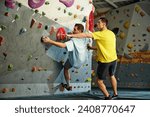 Male instructor teaching man to climb artificial wall. Man training, climbing up the artificial stones. Bouldering activity. Concept of sport, sport climbing, hobby, active lifestyle, school, course