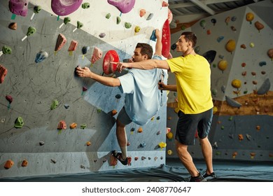 Male instructor teaching man to climb artificial wall. Man training, climbing up the artificial stones. Bouldering activity. Concept of sport, sport climbing, hobby, active lifestyle, school, course - Powered by Shutterstock