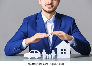 Male Insurance Agent Covering Paper Family, Car And Home At Table, Closeup