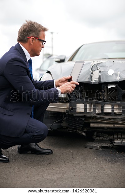 Male Insurance Loss Adjuster With
Digital Tablet Inspecting Damage To Car From Motor
Accident