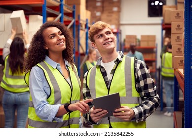 Male Intern With Team Leader Looking At Digital Tablet Inside Busy Warehouse Facility - Powered by Shutterstock