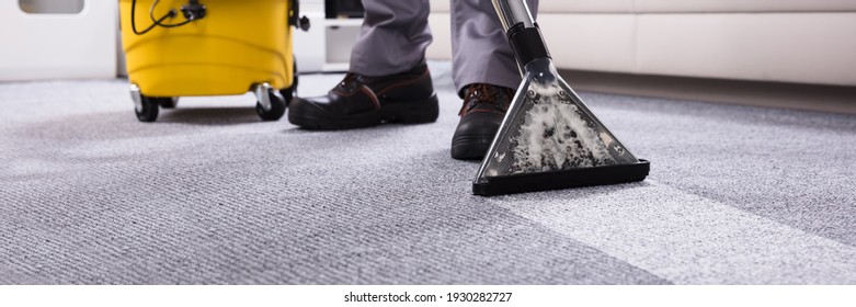 Male Janitor Cleaning Carpet With Vacuum Cleaning In The Living Room