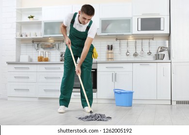 Male Janitor Cleaning Floor With Mop In Kitchen