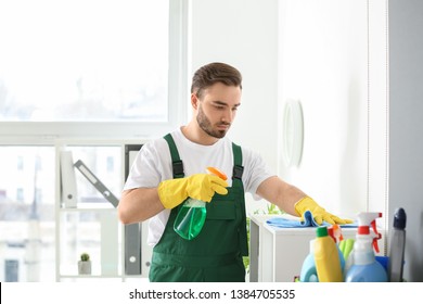 Male Janitor Cleaning Shelf In Office