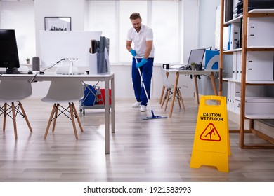 Male Janitor With Mop Cleaning Modern Office Floor