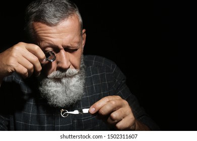 Male jeweler evaluating diamond ring in workshop, space for text