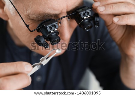 Male jeweler evaluating precious gemstone in workshop, closeup