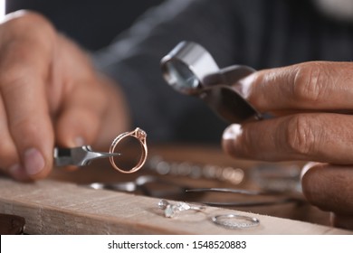 Male jeweler examining diamond ring in workshop, closeup view - Powered by Shutterstock