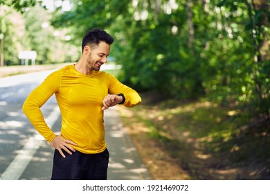 Männlicher Jogger überprüft seine intelligente Uhr beim Laufen im Freien