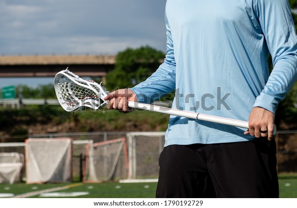 Male\
lacrosse player holding a lacrosse stick on a\
field