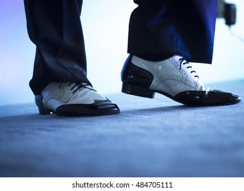 Male Latin And Salsa Dancer In Black And White Jazz Dancing Shoes In Light And Dark On Stage.