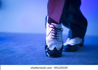 Male Latin And Salsa Dancer In Black And White Jazz Dancing Shoes In Light And Dark On Stage.