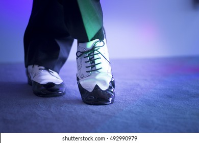 Male Latin And Salsa Dancer In Black And White Jazz Dancing Shoes In Light And Dark On Stage.