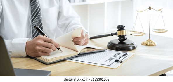 Male Lawyer Or Jurist Working With Litigation Contract Paper Documents Of The Estate Lawsuit, Law Books And Wooden Gavel On Table In Office.