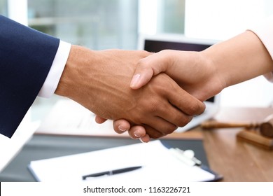 Male lawyer shaking hands with woman over table, closeup