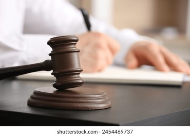 Male lawyer signing documents and judge gavel at table in office, closeup