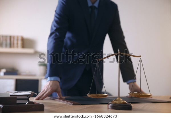 Male Lawyer At Table In Office, Focus On Scales Of Justice