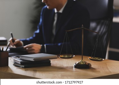 Male Lawyer Working At Table In Office, Focus On Scales Of Justice