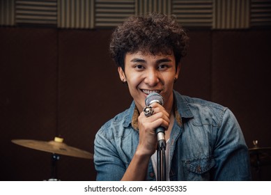 Male Lead Vocalist Singing In Studio With Music Instrument Backg