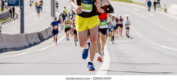 male leader runner marathon running ahead large group people, uphill overpass, endurance sports competition - Powered by Shutterstock