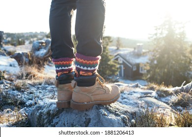 Male Legs In Black Pants And Hand Knitted Wool Traditional Ornament Socks, Leather Suede Winter Boots Or Hiking Shoes. Man On Cold Frosty Mountain Walk In Snow In Scandinavia