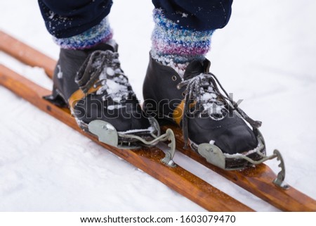 Male legs in multicolored knitted socks stand on a vintage wooden ski