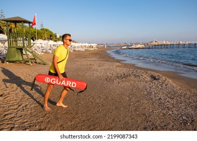 Male lifeguard in action on the Mediterranean beach and saving people in water. Safety while swimming, handsome brunette male lifeguard on the beach, copy space.