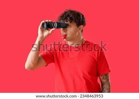 Male lifeguard with binoculars on red background