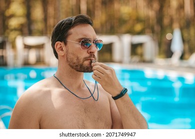 Male lifeguard in sunglasses near the public swimming pool