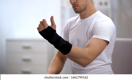 Male looking at hand with titan wrist support, orthopedic equipment, trauma - Powered by Shutterstock