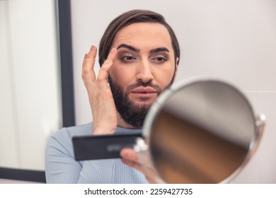 Male looking at himself in the mirror during makeup application - Powered by Shutterstock