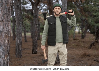 Leñador masculino con hachas en el bosque