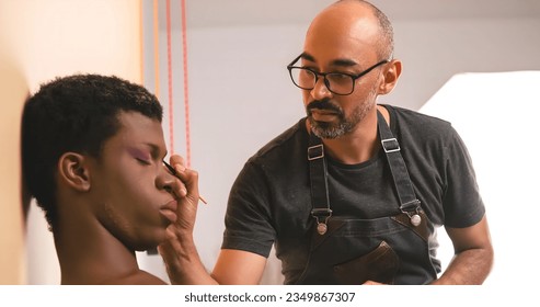 Male makeup artist doing makeup on an African transgender person. - Powered by Shutterstock