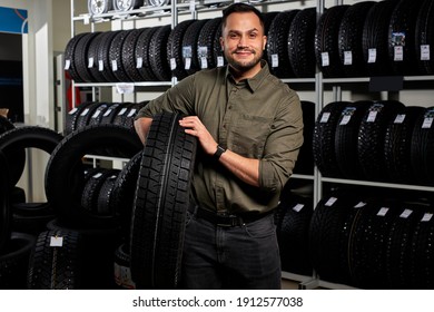 Male Making Purchase In Car Accessories Store, Pleasant And Satisfied Client In Casual Wear Stands Holding Car Tires. Portrait