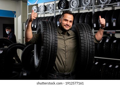 Male Making Purchase In Car Accessories Store, Pleasant And Satisfied Client In Casual Wear Stands Holding Car Tires. Portrait