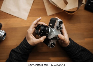 Male man hands adjusts the lens pentax retro camera on a white table. Horizontal