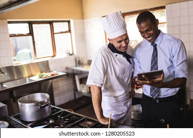 Male Manager And Chef Using Digital Tablet In Kitchen At Hotel