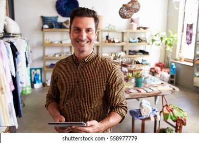 Male Manager With Tablet Computer Standing In Clothes Shop