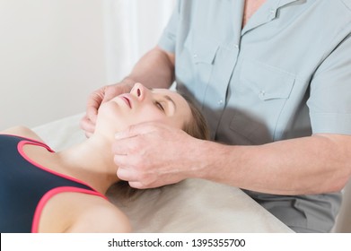 Male Manual Visceral Therapist Masseur Treats A Young Female Patient. Jaw Muscles Warm Up