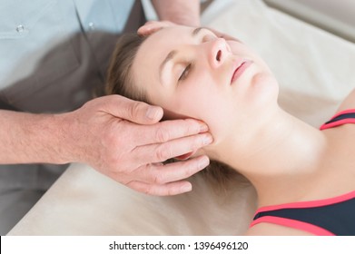 Male Manual Visceral Therapist Masseur Treats A Young Female Patient. Jaw Muscles Warm Up