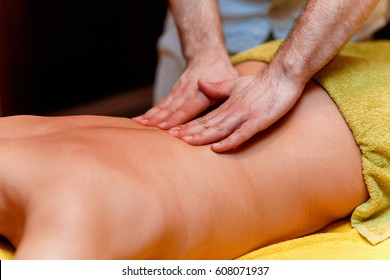 Male Massage Therapist Doing Back Massage To Young Girl At Spa Salon